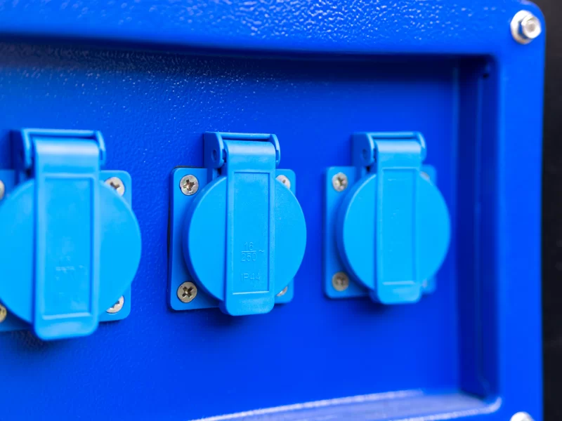 Синие электрические розетки с защитными крышками на синей панели