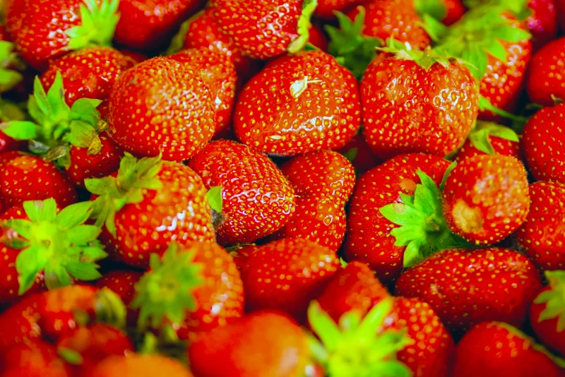 Крупный план спелой клубники с зелеными листьями, сочные ягоды