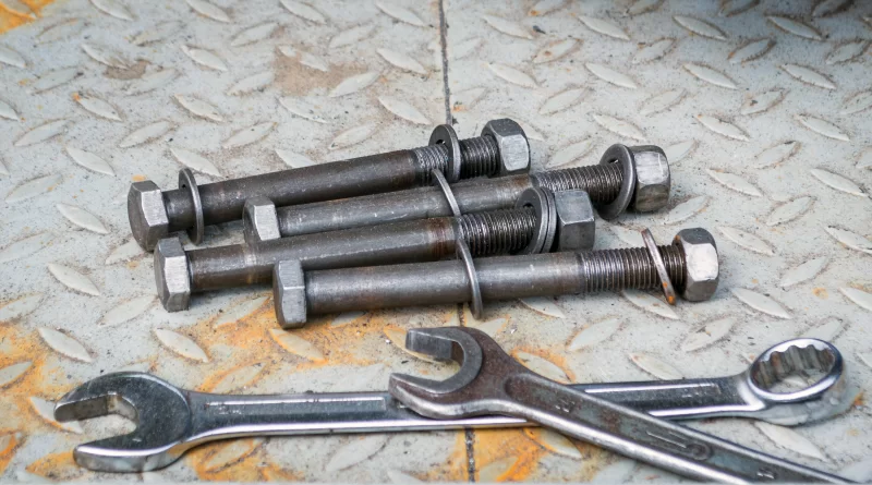 Набор болтов и гаек с гаечными ключами на металлической поверхности