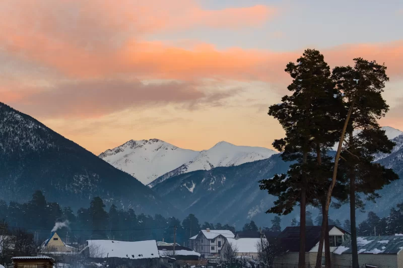Зимний закат в горах: деревня и снежные вершины