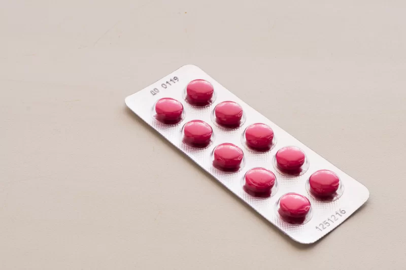 Упаковка розовых таблеток на светлом фоне