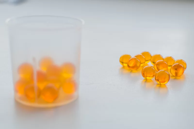 Vitamin capsules and measuring cup on a light background
