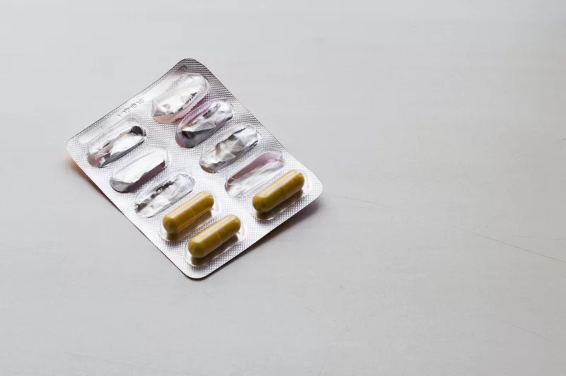 Pill packaging: two capsules in blister pack on grey background