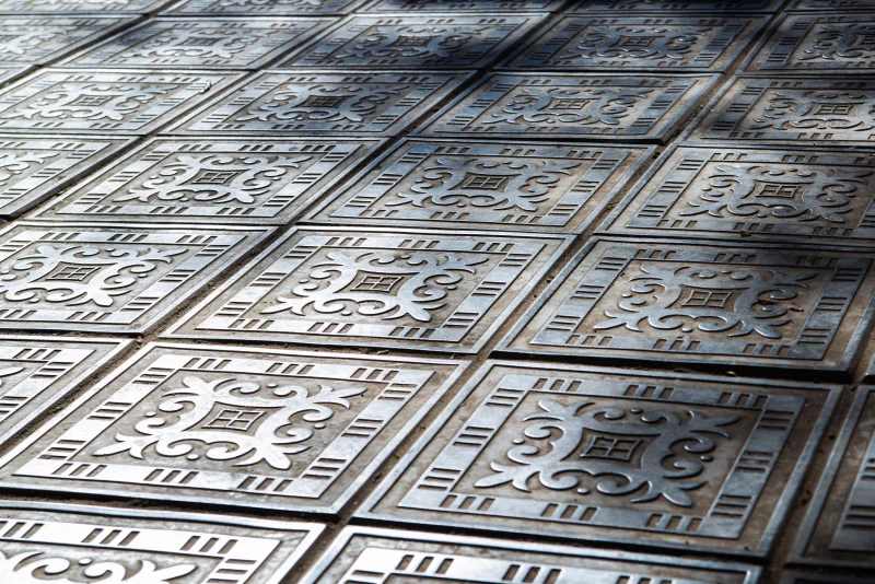 Узоры на больших металлических плитах пола на улице города