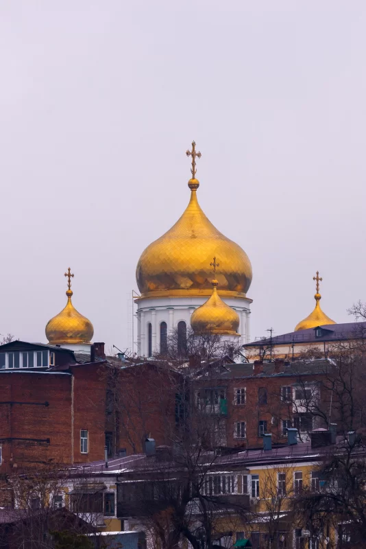 Золотые купола православного храма на фоне пасмурного неба