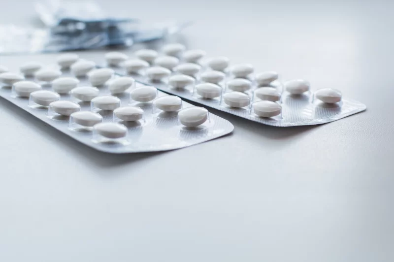 Блистеры с белыми таблетками на светлой поверхности