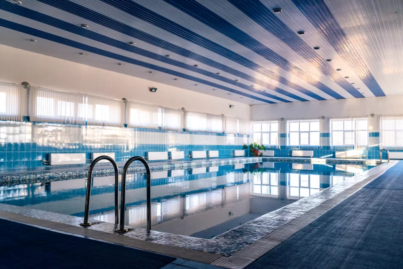 Современный бассейн с голубой водой и полосатым потолком