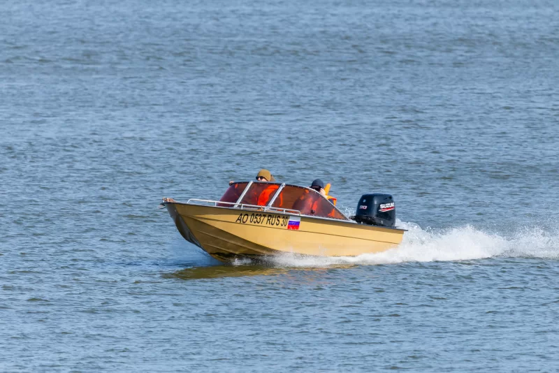 Two man at motor boat racing through the river