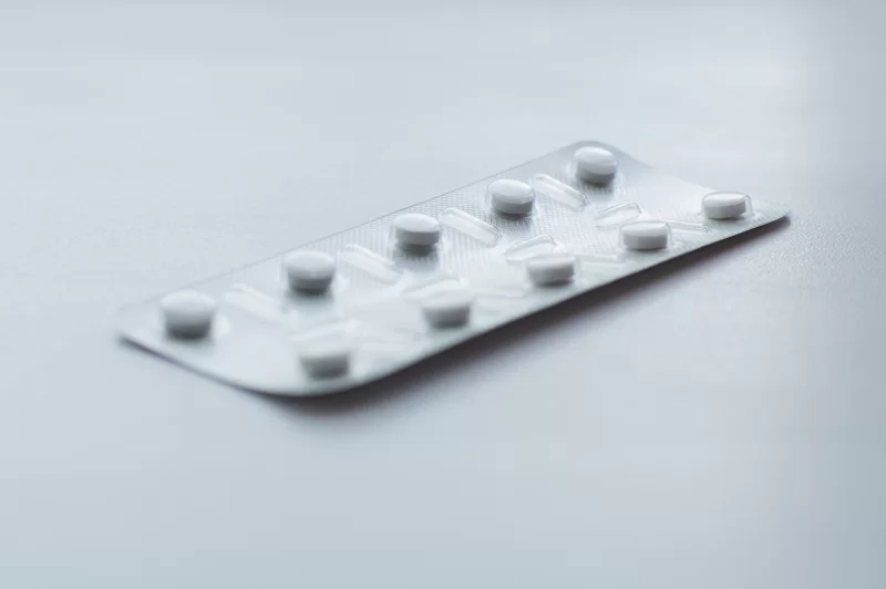 Блистер с белыми таблетками на светлом фоне
