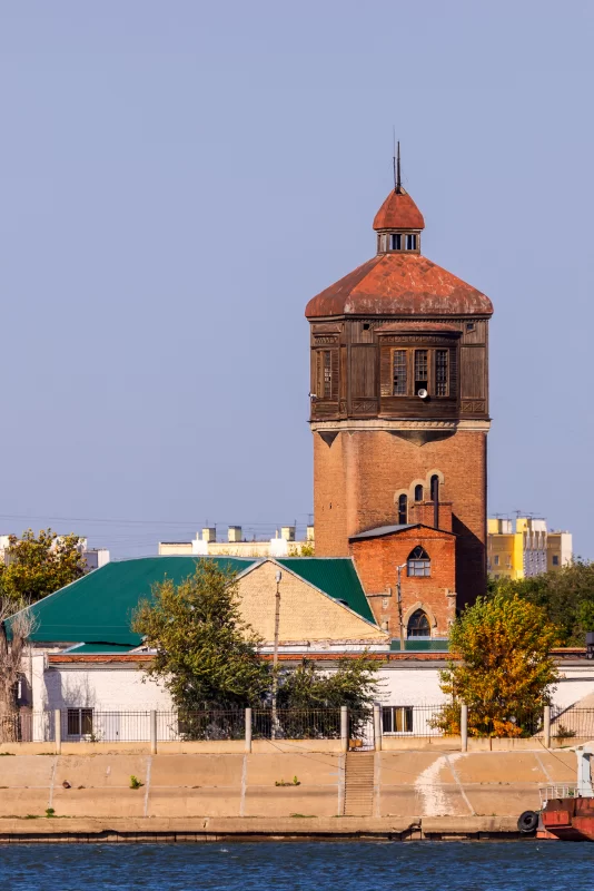 Old water tower against blue sky and river