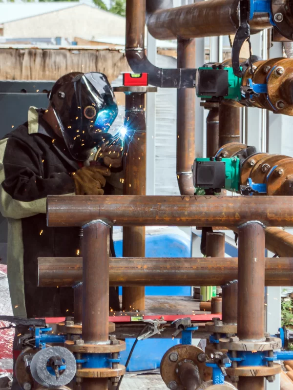 Мастер сварки работает над трубопроводом в промышленных условиях