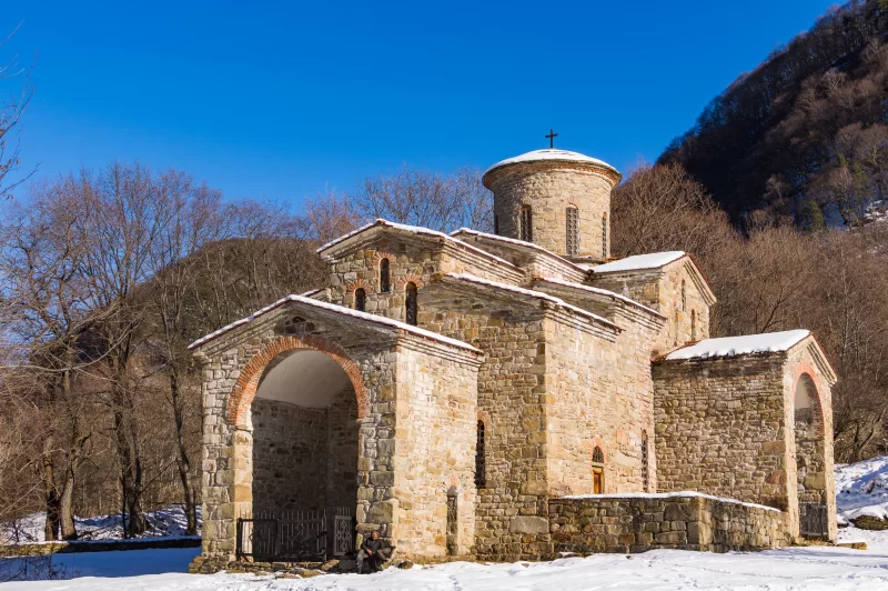Древняя христианская церковь в заснеженных горах Кавказа