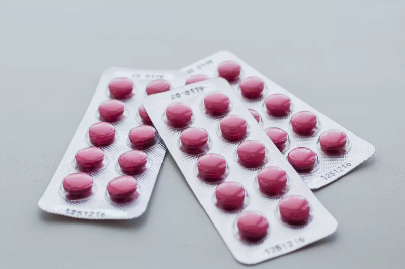 Блистеры с розовыми таблетками на сером фоне