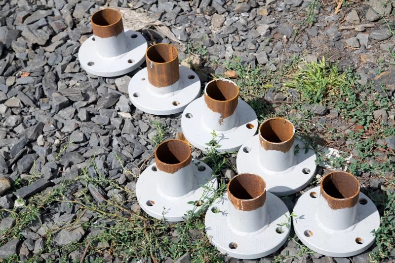 Группа трубных фланцев с ржавчиной на гравийной поверхности