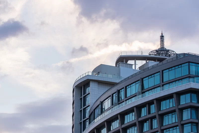 Современное здание с изогнутым фасадом на фоне облачного неба