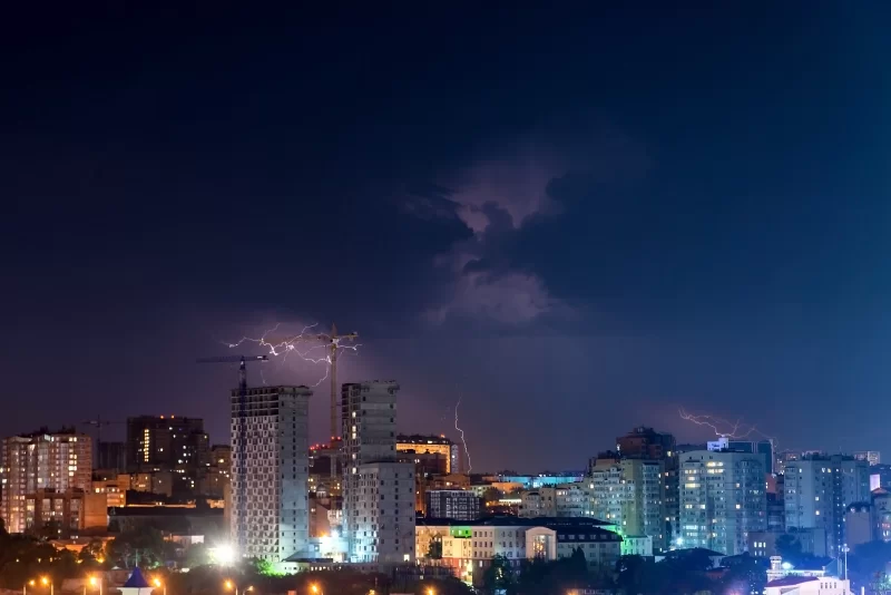 Гром, молнии и шторм в темном ночном небе над городом