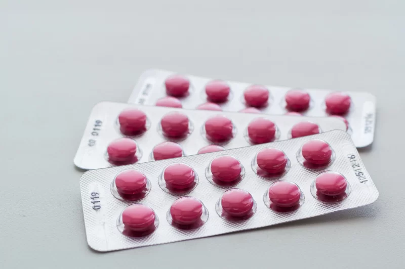 Розовые таблетки в блистерах на сером фоне