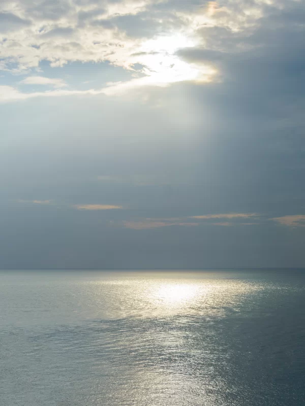 Солнечные лучи пробиваются сквозь облака над морем