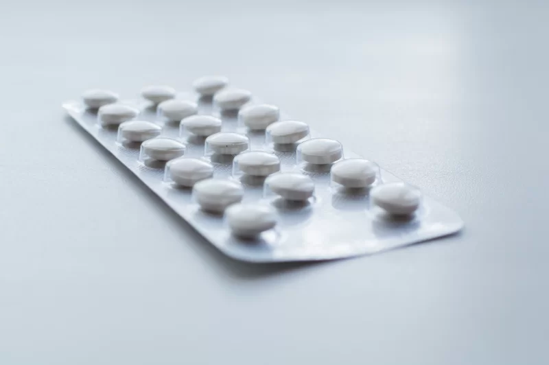 Блистер с белыми таблетками на светлом фоне