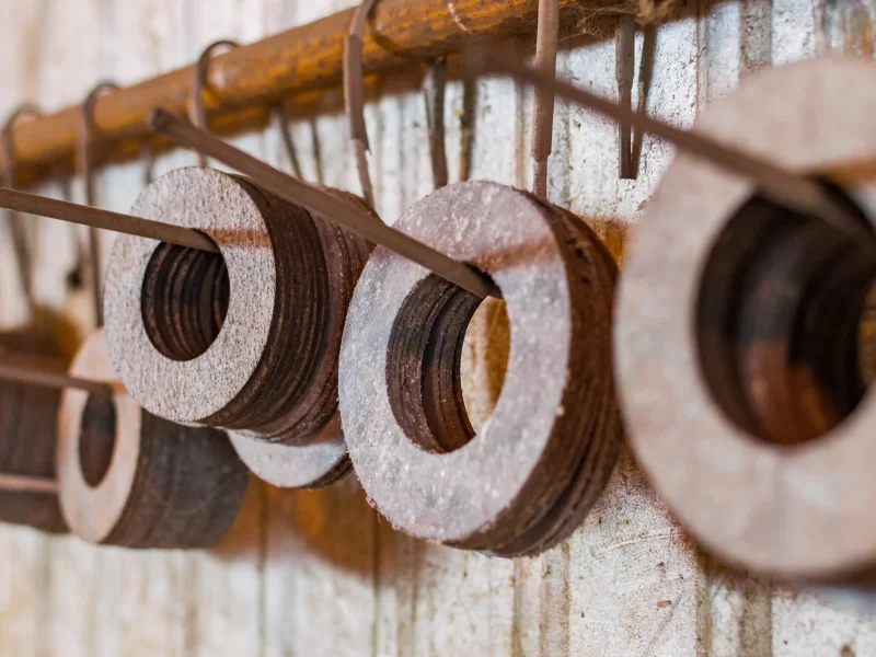 Стопка старых шайб, подвешенных на гвозде в мастерской