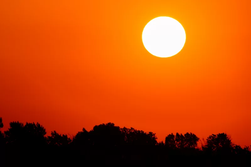 Яркое солнце на оранжевом небе с облаками на закате