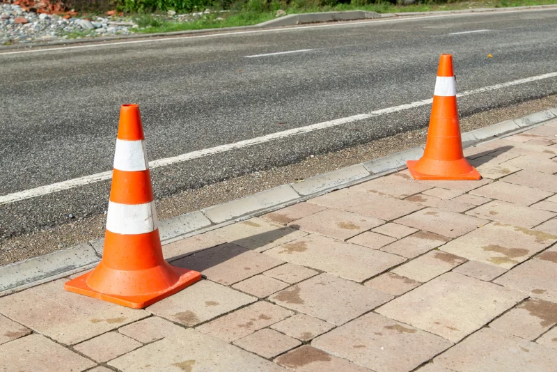 Оранжевые дорожные конусы на тротуаре