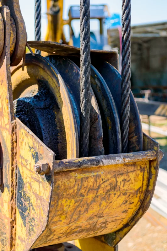 Крупный план грузоподъемного механизма крана: стальные тросы и блоки