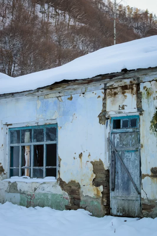 Заброшенный деревенский дом под снежным покровом зимой