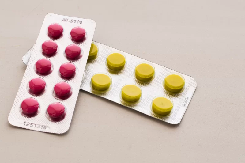 Две блистерные упаковки с таблетками: красные и желтые