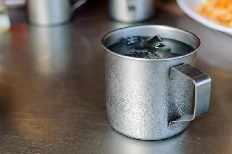 Металлическая кружка с ледяной водой на столе