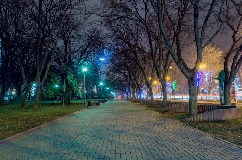 Скамейка в городском парке в сумерках, тропинка