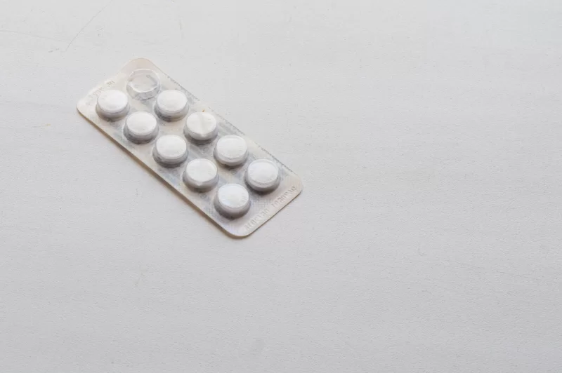 Упаковка белых таблеток на белом фоне