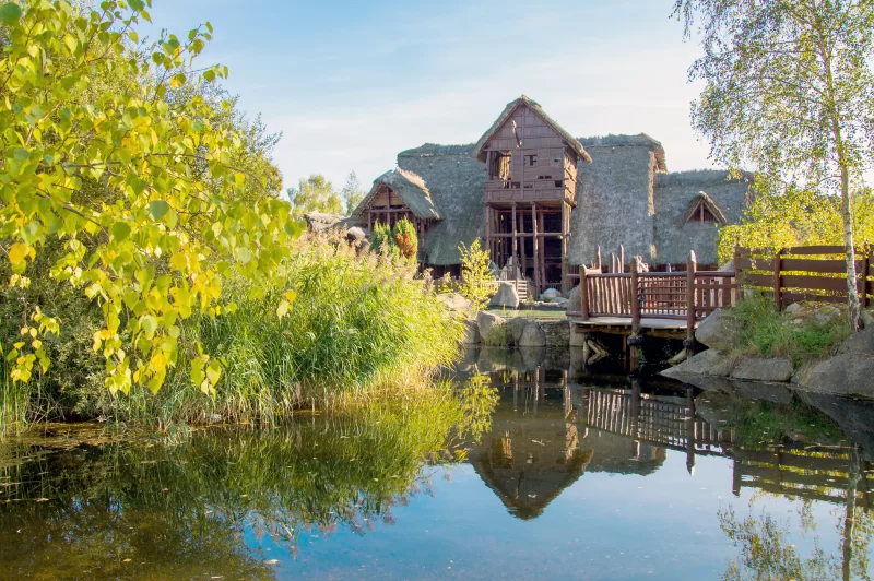 Сказочный дом с соломенной крышей у озера в осеннем лесу