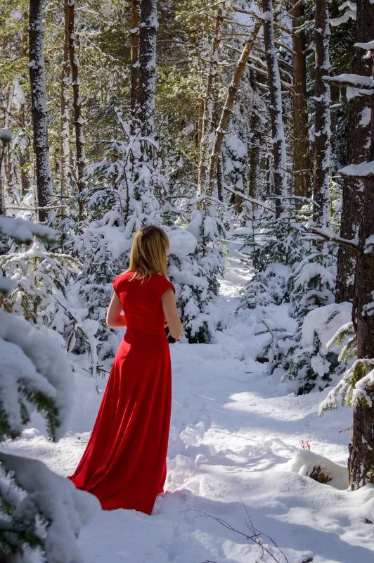 Elegant woman in red dress against a winter forest background