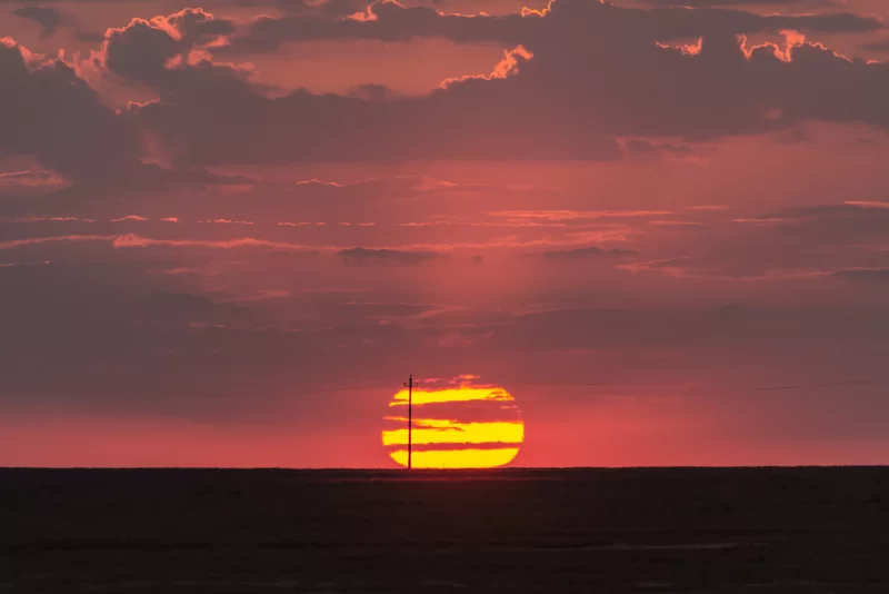 Закат над бескрайней равниной: огненное небо и одинокий столб