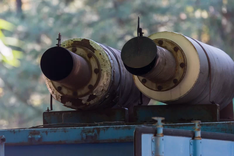 Промышленные трубы с потертостями и ржавчиной на фоне осеннего леса