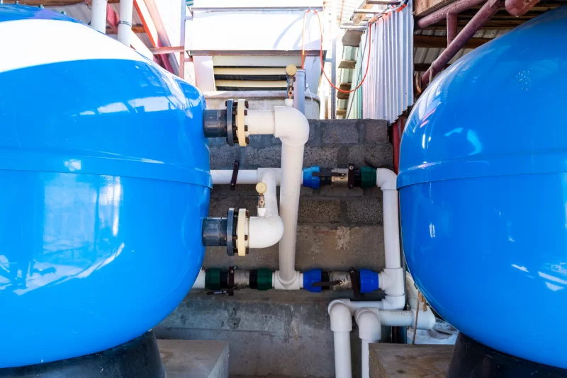 Большие синие расширительные баки с ПВХ-трубами.