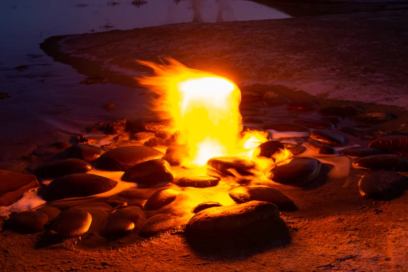 Горящий природный газ на берегу водоема