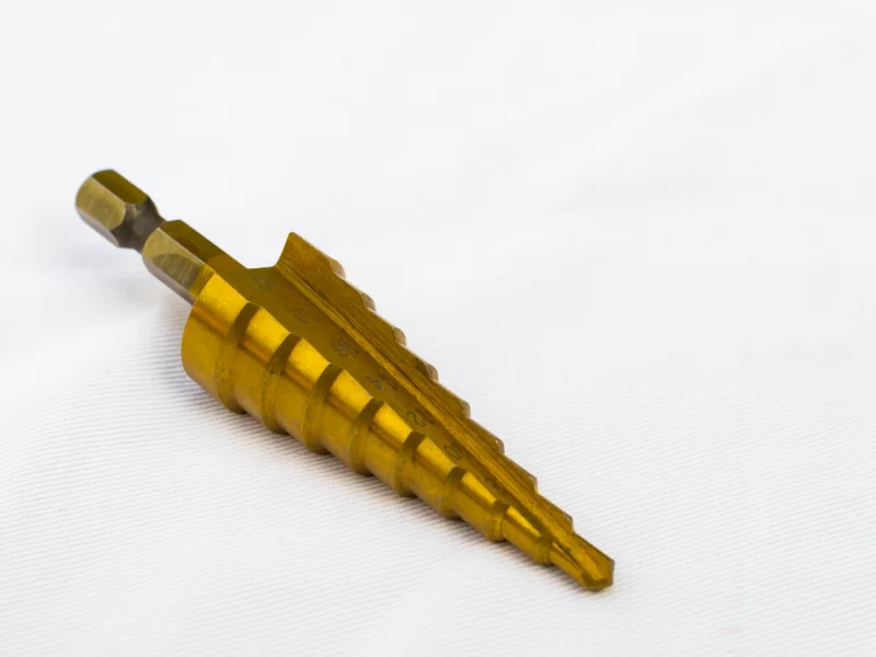 Золотая ступенчатая сверло для металла на белом фоне