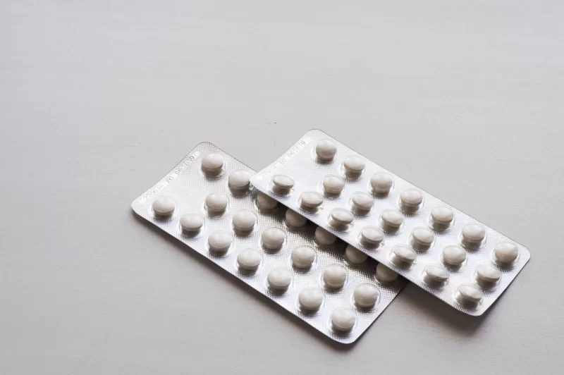 Две упаковки таблеток в блистерах на сером фоне