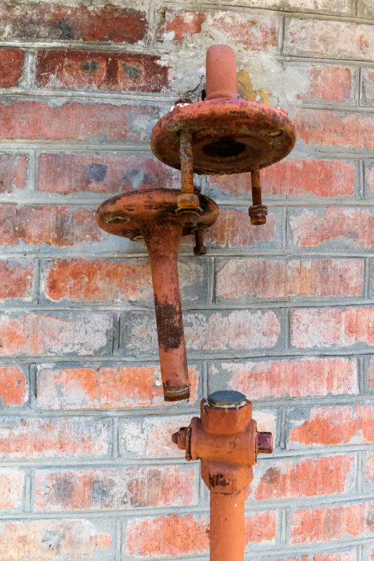 Ржавый газовый кран на кирпичной стене