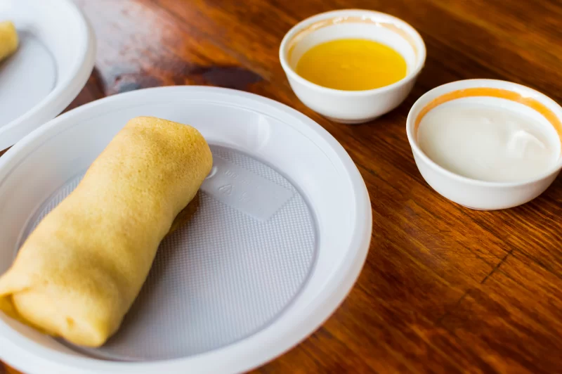 Блинчик с маслом и сметаной на деревянном столе