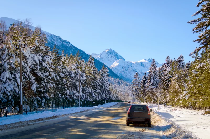 Автомобиль на заснеженной дороге в живописном зимнем горном пейзаже