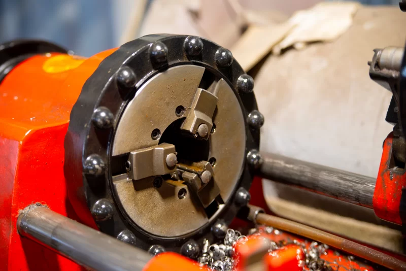 Процесс обработки металла: крупный план патрона токарного станка и стружки