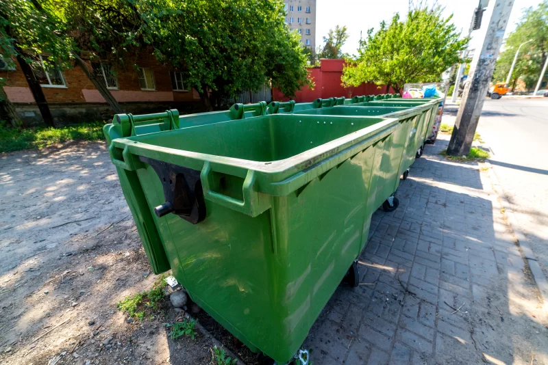 Ряд зеленых мусорных контейнеров на городской улице