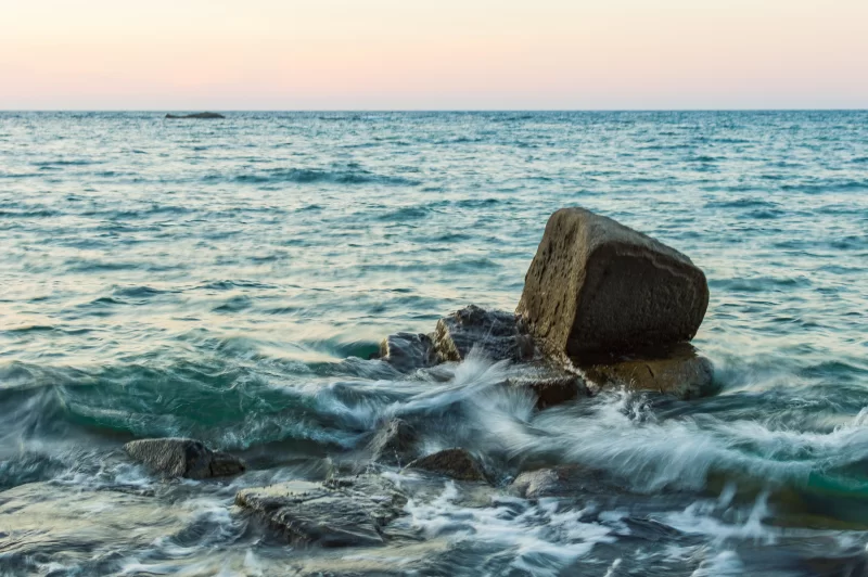 Волна плещется в море о камень
