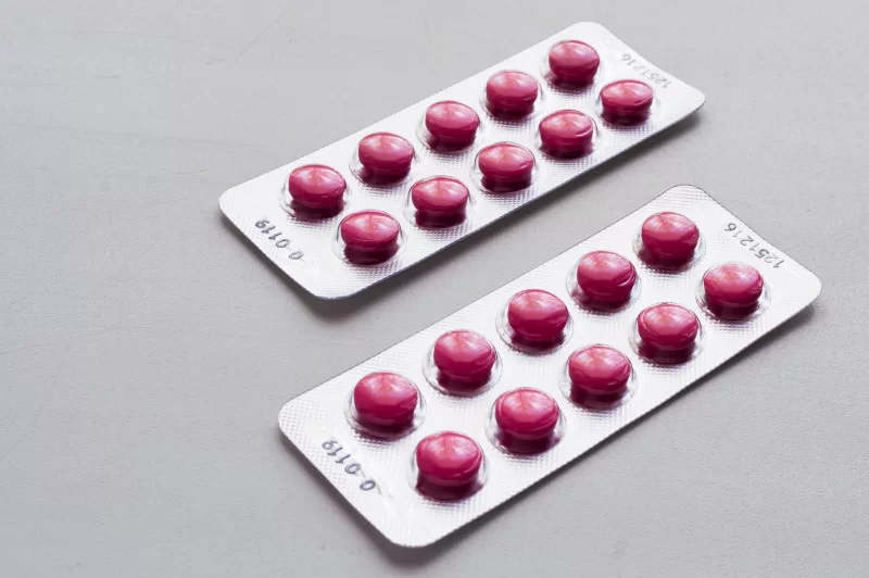 Блистеры с розовыми таблетками на сером фоне