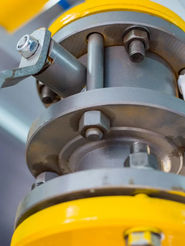 Крупный план промышленного оборудования: клапан с желтой окраской и металлическими деталями